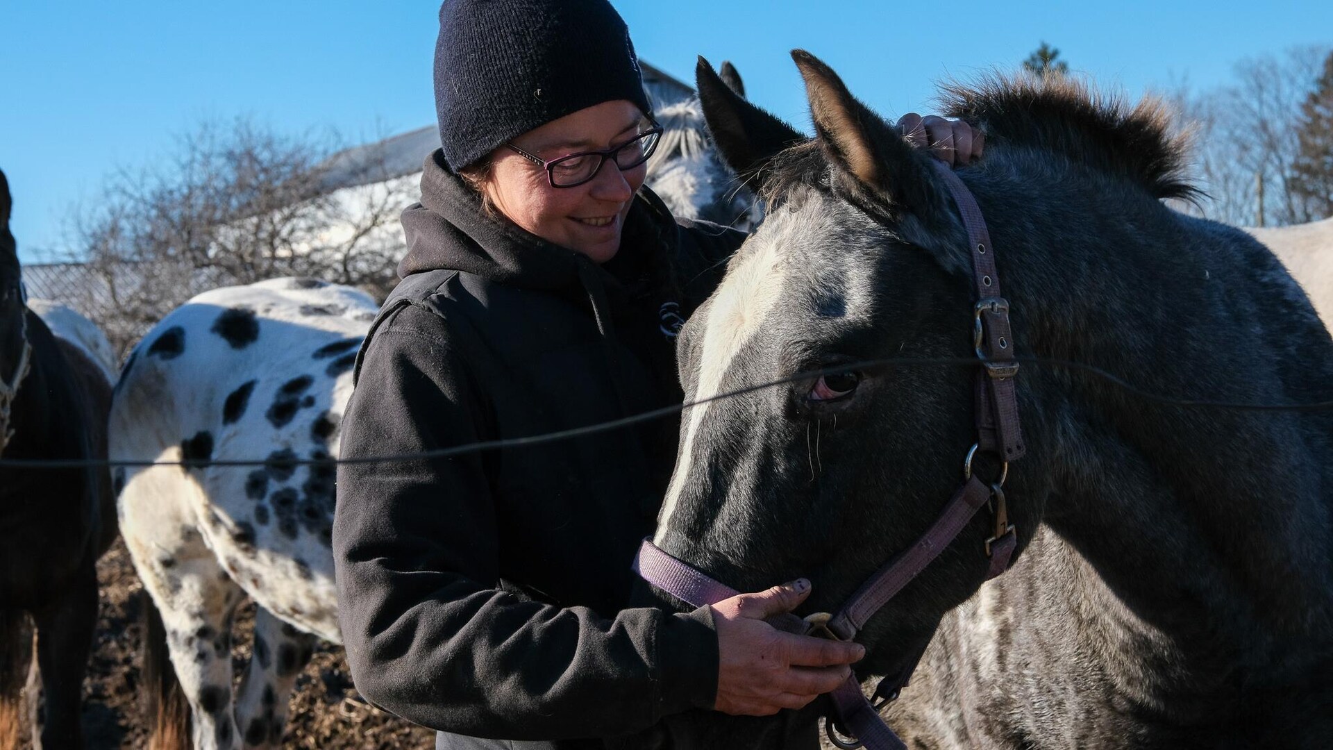 Andréane Thibault caresse son cheval, sourire au visage. 