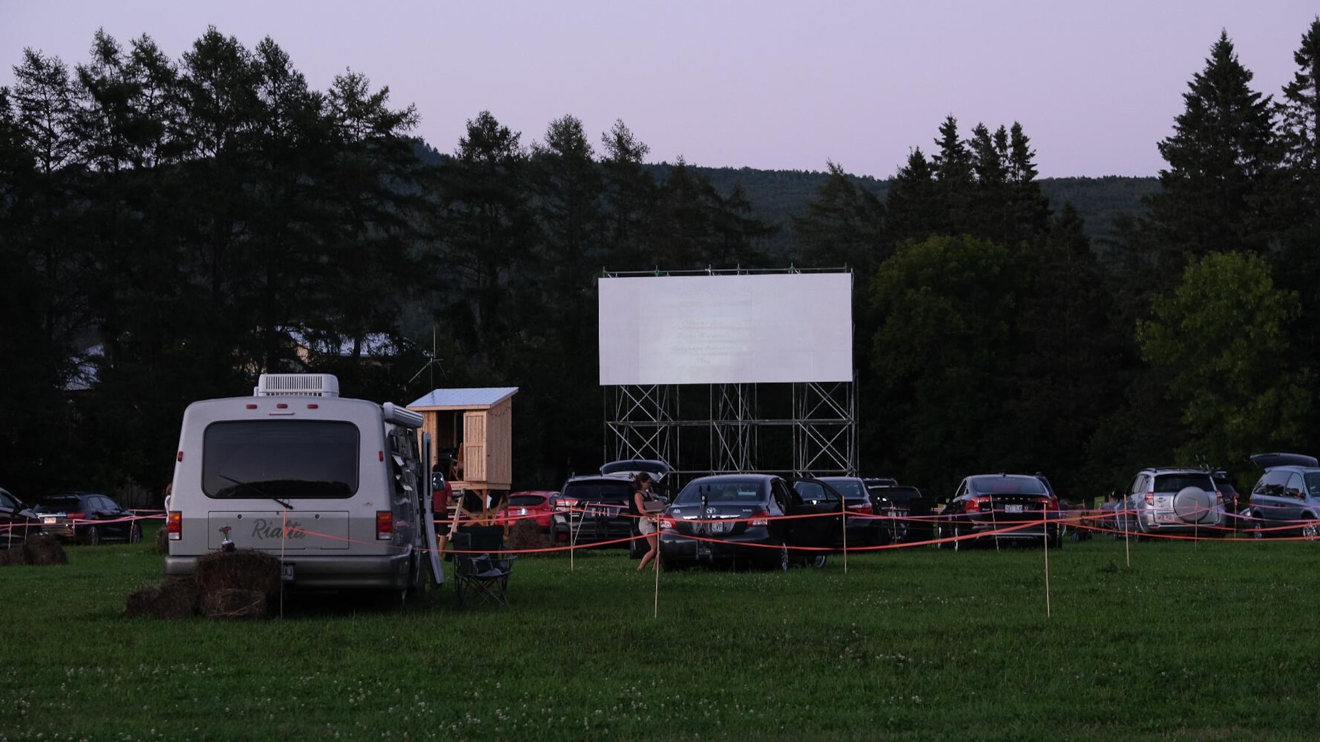 Des véhicules stationnés dans un ciné-parc aménagé sur un terrain gazonné. Des véhicules stationnés dans un ciné-parc aménagé sur un terrain gazonné.