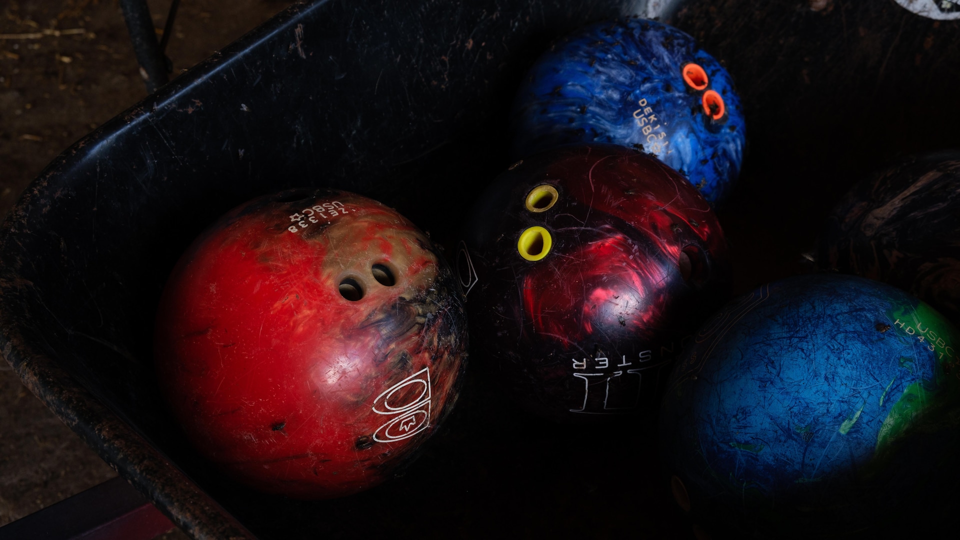 Des boules de quilles rouges et bleues dans une brouette. 