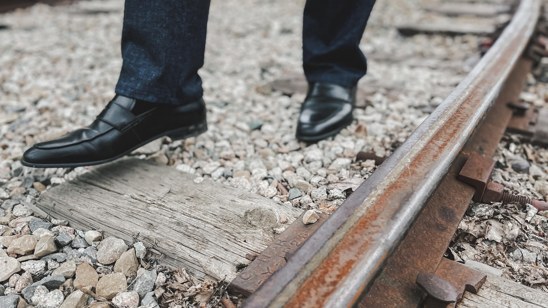 Les jambes de Robert Suraki Watum en habit de travail, qui marche le long d'un chemin de fer.