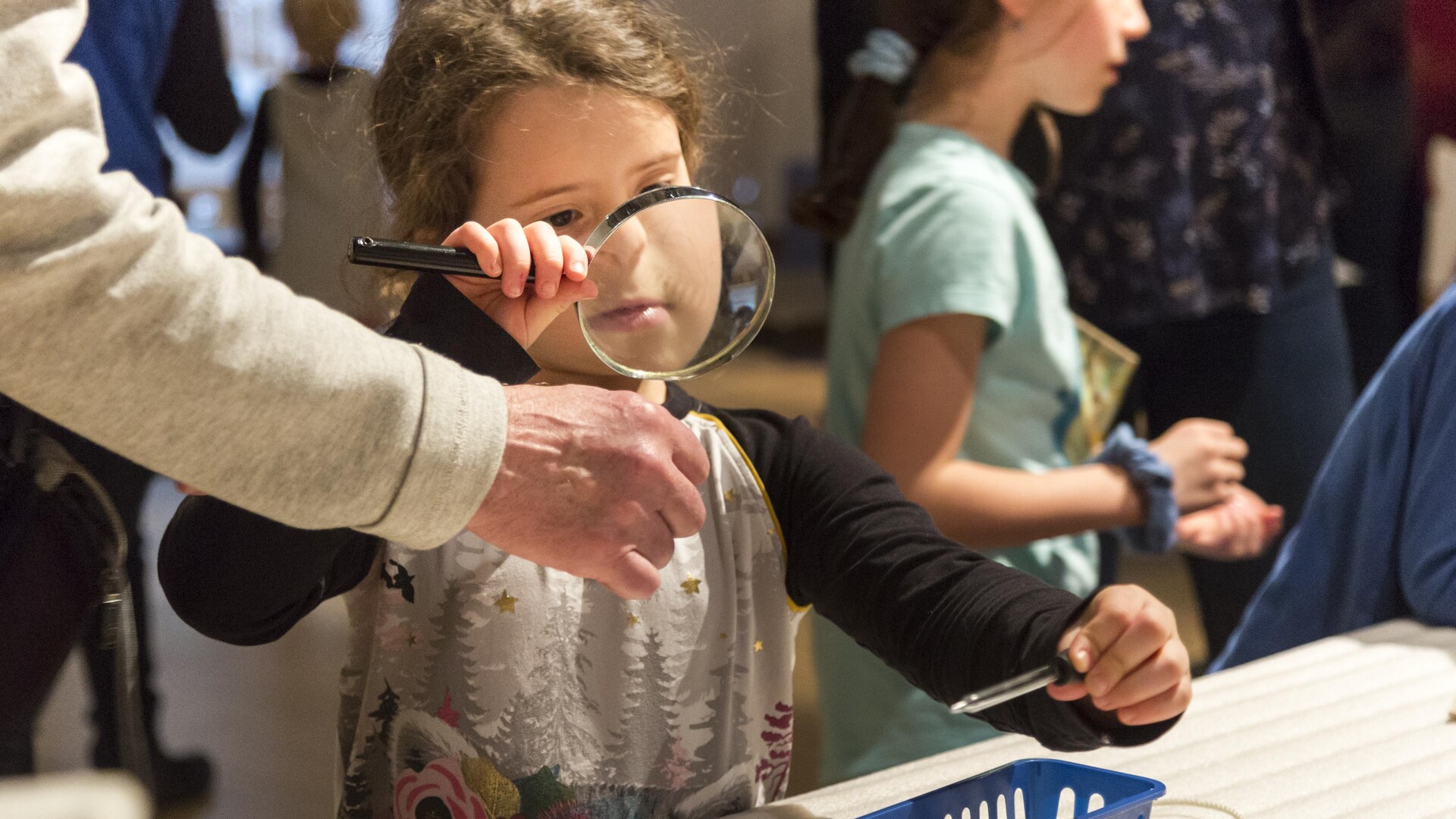 Une petite fille regarde dans une loupe