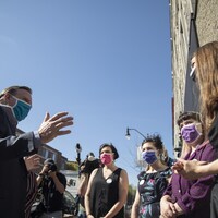 François Legault discute avec un groupe de femmes. Tout le monde est masqué.
