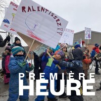 Des enfants et des adultes manifestent devant l'école Les Berges, l'hiver.