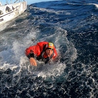 Kevin Escoffier quitte le bateau de Jean Le Cam après son sauvetage.