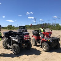 Deux hommes avec chacun leur VTT sur une surface sablonneuse.