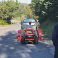 Un homme charge son tracteur-tondeuse sur une remorque.
