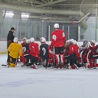 Un groupe de hockeyeurs écoutent leur entraîneur.