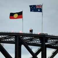 Deux drapeaux flottent au-dessus d'un pont. 