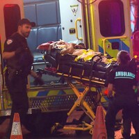 Des ambulanciers placent la civière du blessé dans leur ambulance.