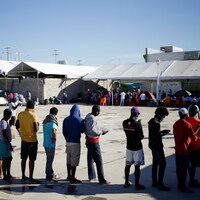 Des migrants font la queue dans un camp. 