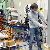 Un homme travaille sur une borne de recharge électrique dans une usine.