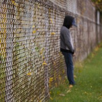 Un adolescent appuyé sur une clôture.