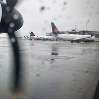 Des avions sont stationnés devant l'aéroport d'Halifax lors une journée pluvieuse.