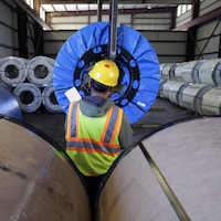 Un travailleur d’une usine du Texas se sert d’un monte-charge pour transporter un rouleau de feuilles métalliques. 