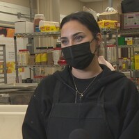 Alicia Morrow porte un masque et est interviewée dans les locaux de l'organisme. 