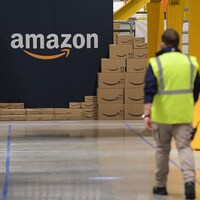 Un employé marche vers un mur affichant le logo d'Amazon.