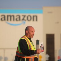 Le syndicaliste Steve Robertson tendant une brochure d'information devant un entrepôt d'Amazon.