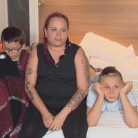 Amélie Sauvé et ses deux enfants sur un lit d'hôtel.
