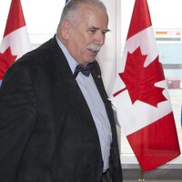 Photo d'André Arthur en costume devant deux drapeaux du Canada.