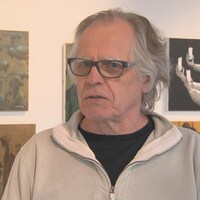 Un homme répond aux questions d'une journaliste dans une galerie de Québec où ses oeuvres sont exposées.