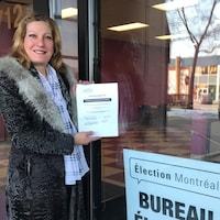 La candidate du parti Ensemble Montréal, Angela Gentile, pose tout sourire avec sa feuille de candidature devant le bureau d'Élection Montréal.