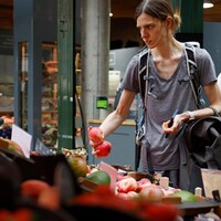 Une femme achète des fruits dans un marché de Londres.