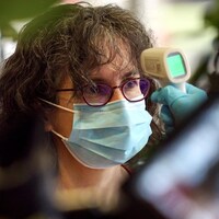 Un médecine prend la température de la patiente.