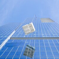 Une unité de ventilation tirée par un monte-charge devant un gratte-ciel.