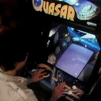 Un jeune homme joue au jeu vidéo Quasar dans une arcade.