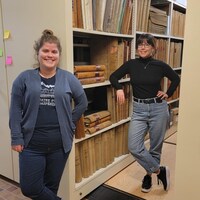 Deux femmes devant une rangée de livre ancien dans une salle des archives