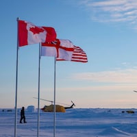 Des drapeaux flottent alors que des hélicoptères sont posés dans l'Arctique.