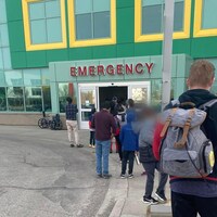 Des enfants et leurs parents attendent devant l'entrée de l'hôpital pour enfants de l'Alberta. 