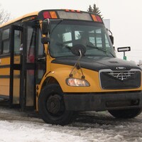 Un jeune joueur de hockey descend d'un autobus scolaire.