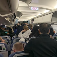 Des passagers se lèvent pour sortir d'un avion Air Canada en décembre 2021.