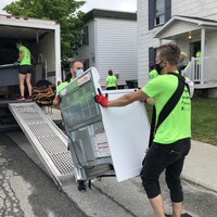 Des bénévoles entrent un four dans un camion de déménagement. 