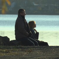 Le couple, assis sur le bord de l'eau, regarde au loin.