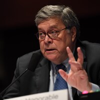 Bill Barr gesticule assis à une table.