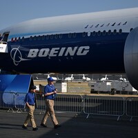Des membres du personnel de la compagnie passent devant un Boeing 777-9.