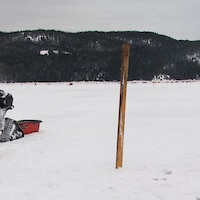 Une motoneige et un poteau de bois sur une baie gelée l'hiver.