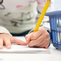 Un enfant en train d'écrire sur une feuille.