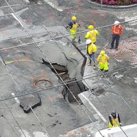 Un trou dans la chaussée et des employés de la construction autour.