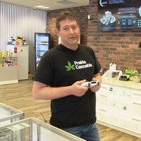 Un homme tient un menu électronique dans sa boutique de cannabis à Saskatoon.