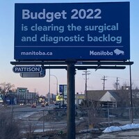 Un panneau publicitaire affirme que le Budget 2022 du gouvernement manitobain permettrait de remédier au retard dans les opérations chirurgicales.
