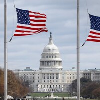 Vue panoramique du Capitole, derrière des drapeaux des États-Unis.