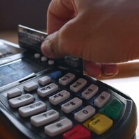 Gros plan sur quelqu'un qui passe sa carte de crédit dans un terminal de paiement électronique.