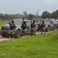 Une dizaine d’hommes armés à côté de camions blindés.