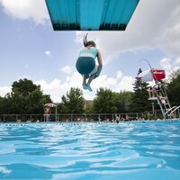 Une enfant saute dans une piscine publique.