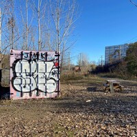 Un terrain avec au centre une table et à gauche un panneau orné d'un graffiti.