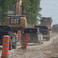 Des véhicules passent sur une route en gravier dans un chantier de construction sur la route 148 à Pontiac.