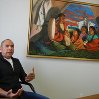 Un homme devant une peinture autochtone. 
